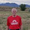 Dressed in jeans and a red Cancer Support Community T-shirt, Paul smiles outside with the Boulder foothills behind him