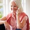 a seated older woman smiling and talking on the phone