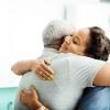 A side view of a female doctor hugging an older man in a clinic