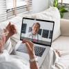 An older man wearing glasses talks with a health professional in a video call