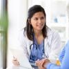 A seated doctor discussing a file with a patient