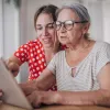 Two seated women review information on a tablet