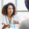 A female doctor talks with an unseen young woman holding a patient information brochure