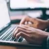 Man's hands typing on laptop keypad