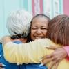 Three women give one another a friendly hug on a sidewalk