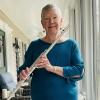 Lyn holds a flute on an enclosed front porch