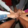 Many people hands meet at the center of their circle