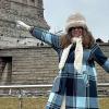 Olga pictured in winter coat and hat stands near the Statue of Liberty  