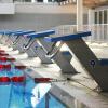 A row of blue starting blocks line the edge of an empty swimming pool