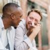 Two men sit together on a city apartment step holding hands